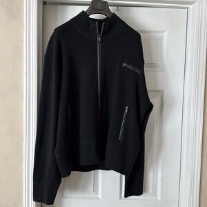 Black 100% merino wool with leather trim from zipper and front pockets.